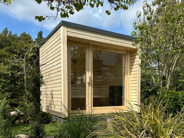 Moderne Außensauna INA Seitenansicht im Garten mit Glasfront