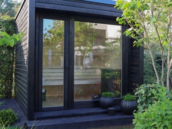 Moderne Außensauna INA Seitenansicht im Garten mit Glasfront