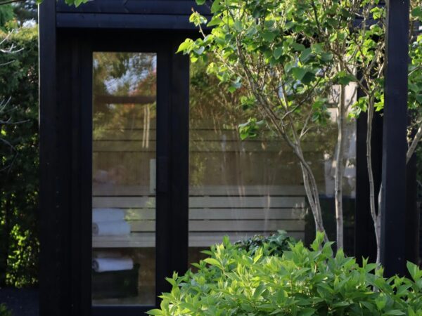 Moderne Außensauna INA Seitenansicht im Garten mit Glasfront